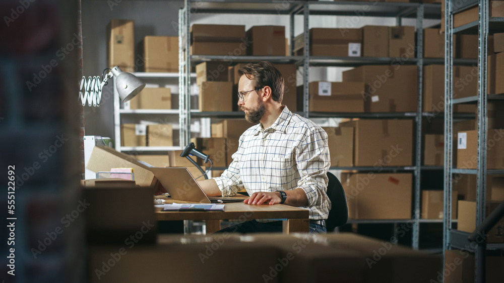 Male Inventory Manager Using Laptop Computer in Storeroom, Communicating with Clients, Writing Down Projects. Stylish Small Business Owner Working in Warehouse, Fulfilling Orders for Customers. - obrazy, fototapety, plakaty 
