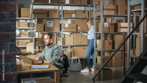 Close Up Portrait of Warehouse Inventory Manager and Worker Using Laptop Computer, Preparing a Parcel for Shipping. Small Business Owners Working in Storeroom, Preparing Online Orders for Clients.