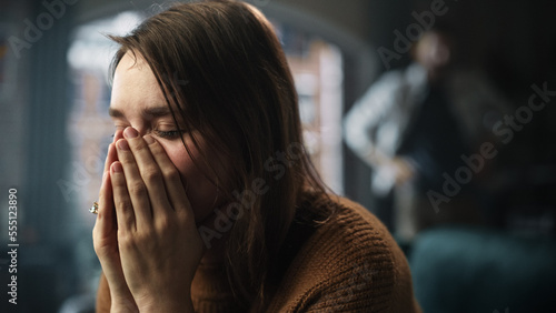 Portrait of Sad Crying Woman being Harrased and Bullied by Her Partner. Couple Arguing and Fighting Violently. Domestic Violence and Emotional Abuse. Rack Focus with Boyfriend Screaming in Background photo
