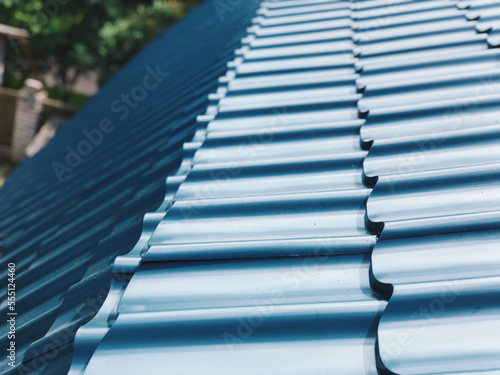 Glossy shiny blue metal tile at an angle on the roof of a house