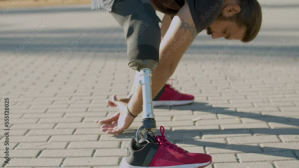 Strong man with artificial leg doing stretching exercises outside ...