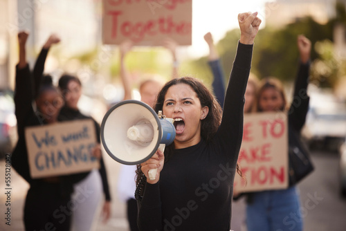 Woman, megaphone and fist in community protest for change, gender based violence or equality in the city. Angry women activist standing together in march strike for human rights or government action