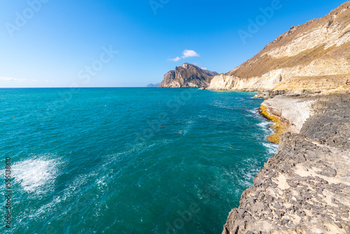 The Dhofar Mountains and white sandy beach along the Arabian Sea at Salalah, Oman.