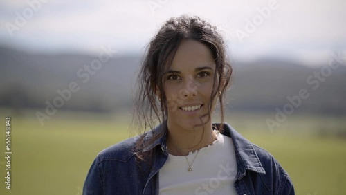 Closeup view of hands of a woman holding carton box with fresh vegetables and fruit, camera moving to the face of the girl smiling and happily walking in the green field from the small rural farm