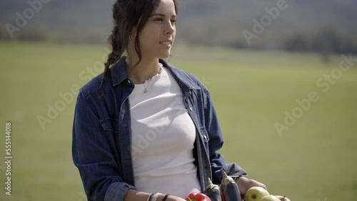 Pretty young woman holding in the hands box of organic natural food. Concept of bio agriculture and and seasonal harvesting by small farmers and healthy diet in the nature