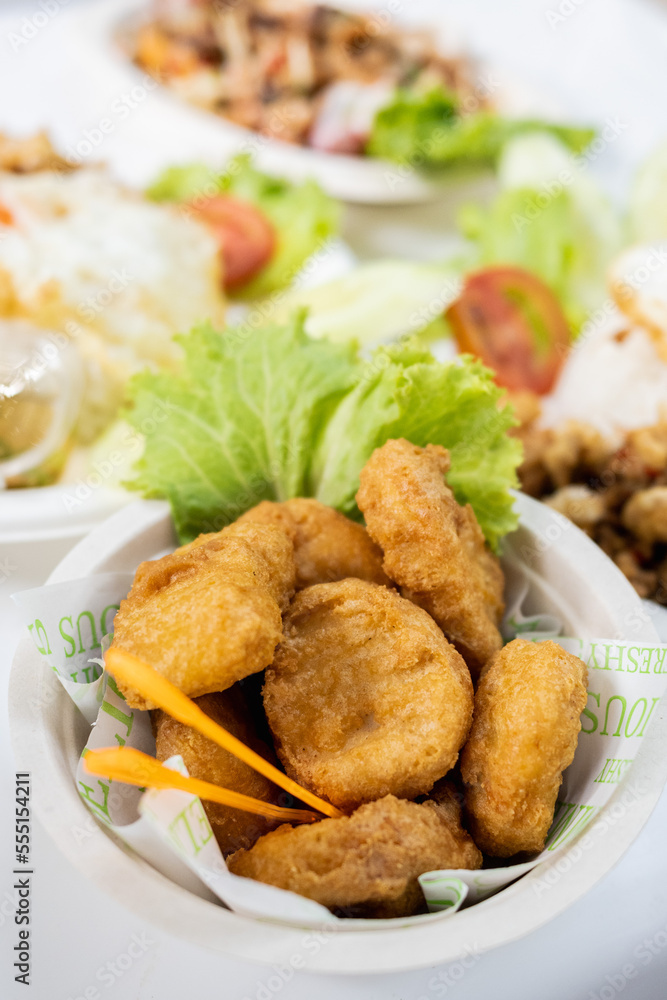 Nuggets in white paper cup with vegetables and other food Nuggets in white paper cup with vegetables and other food