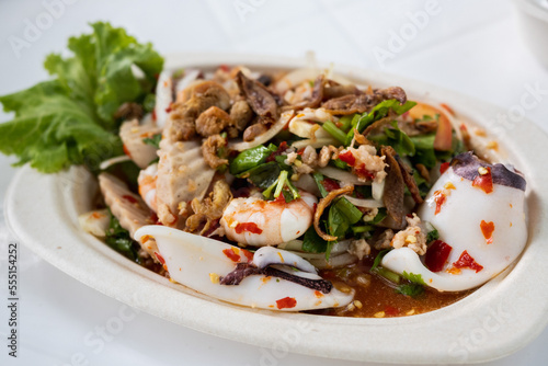 Spicy salad with seafood and vegetables decorated in a white plate