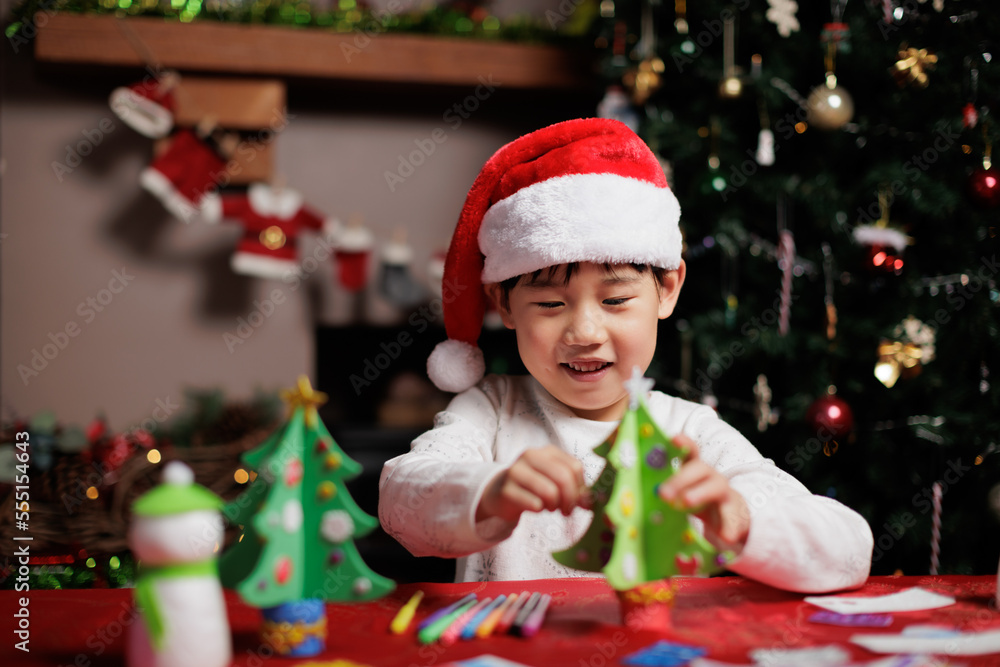 young girl wearing santa hat was making Christmas craft at home young girl wearing santa hat was making Christmas craft at home