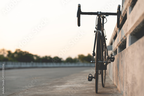 Road bike parked on a beautiful road sunset, on the bridge warm light with copy space.