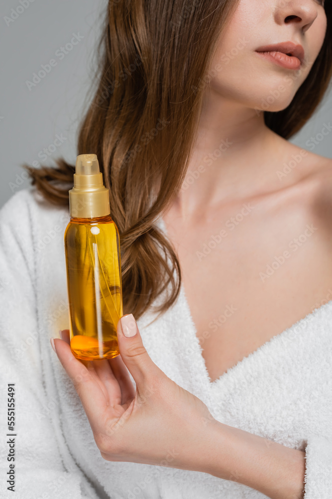 cropped view of young woman with shiny hair holding bottle with oil isolated on grey cropped view of young woman with shiny hair holding bottle with oil isolated on grey