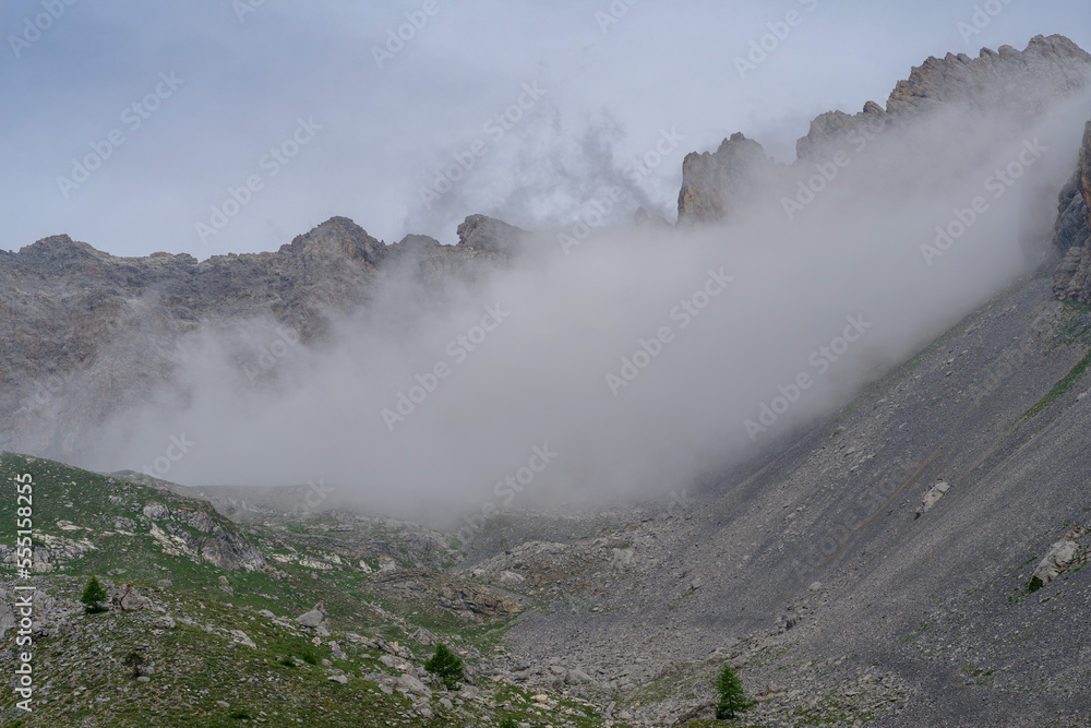Hiking in Maira Valley, Italy. Mountain peaks emerging from the clouds