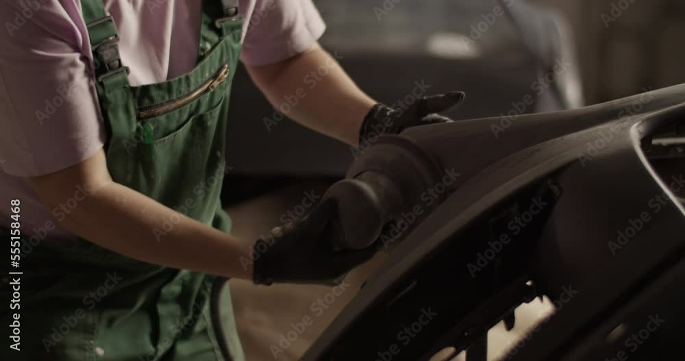 Female garage worker removing paint from bumper Female garage worker removing paint from bumper