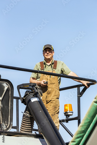 Farmer standing on top of hopper with blue sky in the background; Beiseker, Alberta, Canada photo