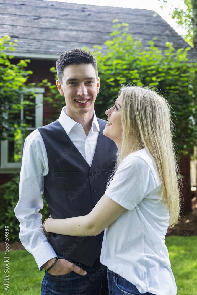 Portrait of a young couple standing in a backyard; Bothell, Washington, United States of America Portrait of a young couple standing in a backyard; Bothell, Washington, United States of America