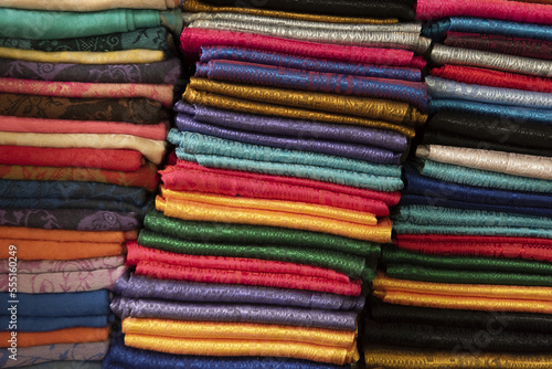 Close-up of three piles of folded silk scarves in a variety of colours; Bangkok, Thailand photo
