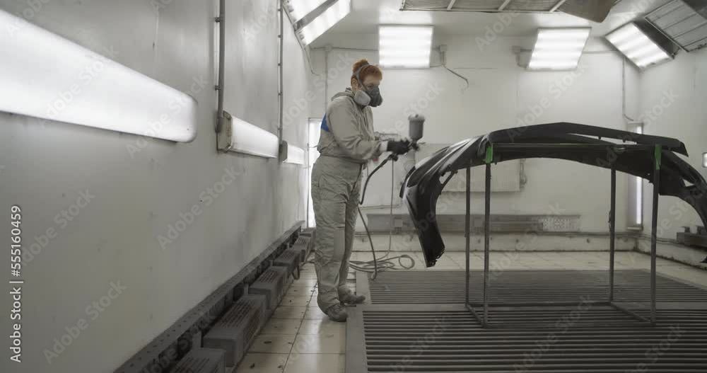 Craftswoman painting car bumper in workshop Craftswoman painting car bumper in workshop