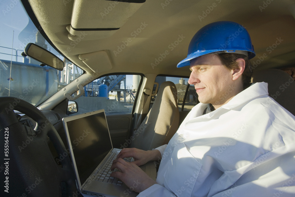Engineer working on a laptop in a car Engineer working on a laptop in a car