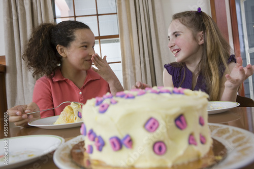 Two girls eating birthday cake and smiling photo