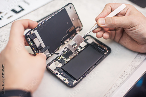 Cell phone repair at service center, smartphone disassembling and diagnostics, repairman workplace top view