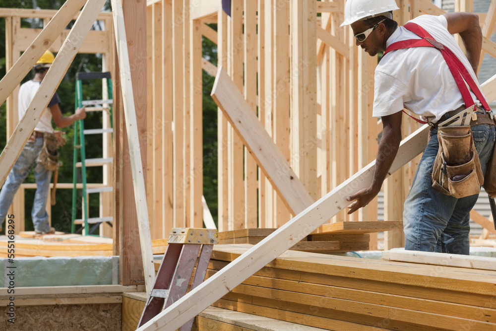Carpenter lifting a framing board Carpenter lifting a framing board