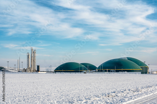 Moderne Biogasanlage in ländlicher, winterlicher Region vor blauem Himmel