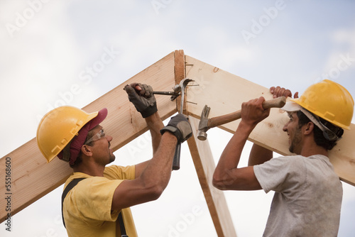 Carpenters adjusting rafters with hammer and nails and pry bar photo