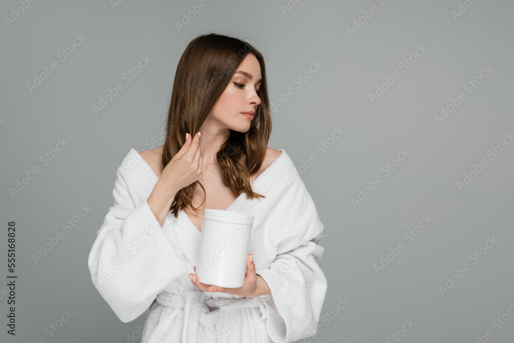 young woman with healthy hair holding container while applying treatment mask isolated on grey young woman with healthy hair holding container while applying treatment mask isolated on grey