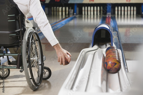 Low section view of a man with a Spinal Cord Injury playing ten pin bowling photo