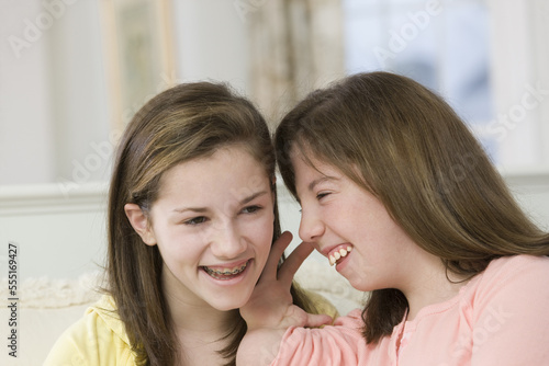 Teenage girl whispering to her sister, one with birth defect