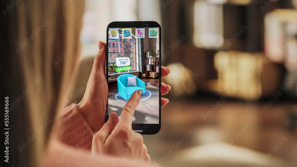 Decorating Apartment: Woman Holding Smartphone, using Augmented Reality Interior Design Software Chooses 3D Furniture for Home. Pick a Stylish Chair for the Living Room. Over Shoulder Close-up Screen Decorating Apartment: Woman Holding Smartphone, using Augmented Reality Interior Design Software Chooses 3D Furniture for Home. Pick a Stylish Chair for the Living Room. Over Shoulder Close-up Screen
