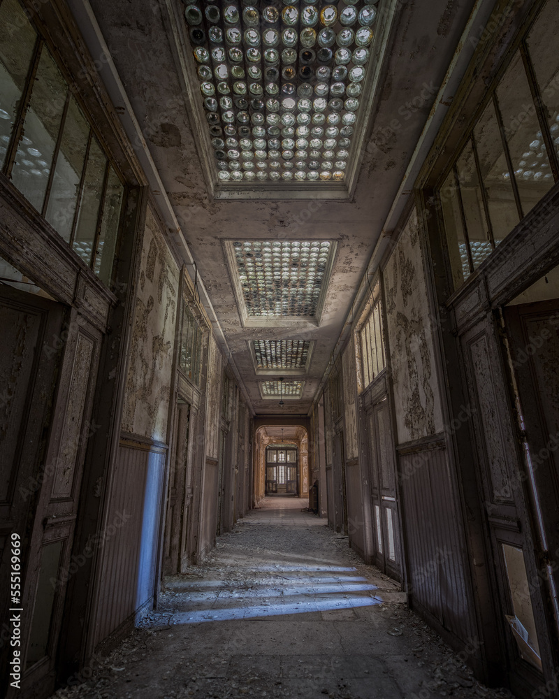 Vertical shot of the corridor of an old abandoned building with the decayed doors
