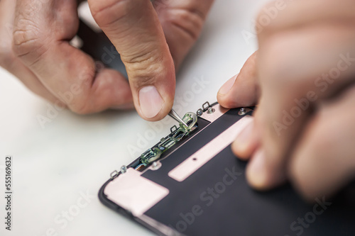 Cell phone repair at service center, smartphone disassembling and diagnostics, repairman workplace top view