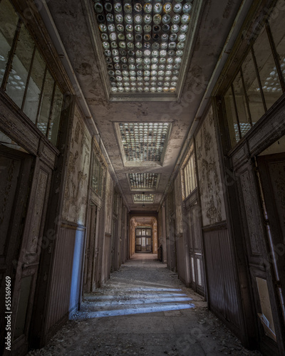 Vertical shot of the corridor of an old abandoned building with the decayed doors 