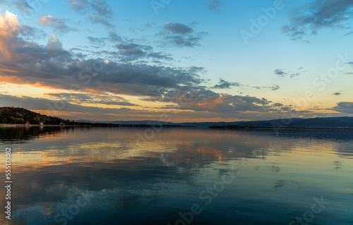 Sunset landscape. Lake water surface with reflection of clouds in the water