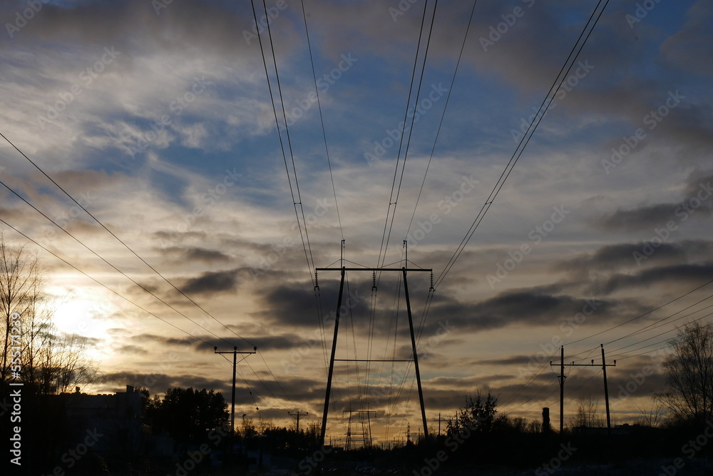 high voltage power lines against a beautiful sunset on a cloudy day
