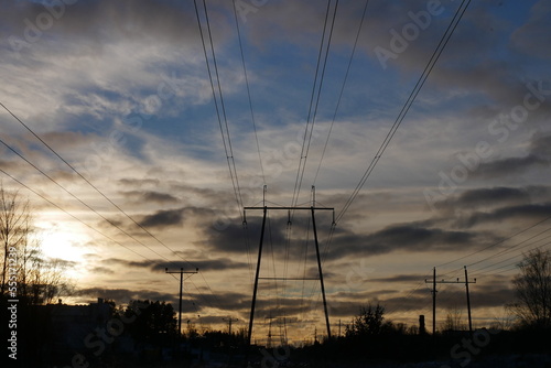high voltage power lines against a beautiful sunset on a cloudy day