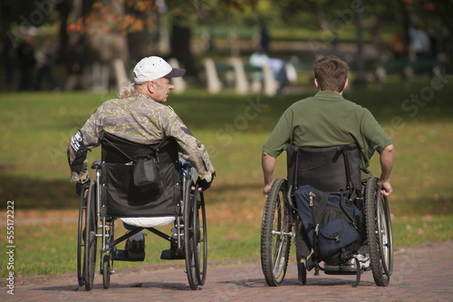 Two war veterans in wheelchairs in a park photo