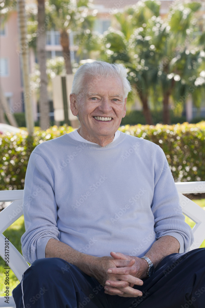 Portrait of a senior man sitting on a park bench and smiling Portrait of a senior man sitting on a park bench and smiling