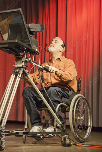 Man in wheelchair with muscular dystrophy using a TV camera and a teleprompter in studio photo