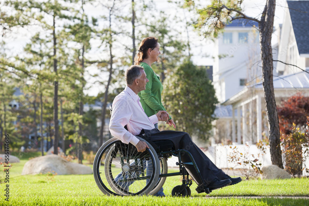 Couple looking at their neighborhood while he is in a wheelchair with a spinal cord injury Couple looking at their neighborhood while he is in a wheelchair with a spinal cord injury