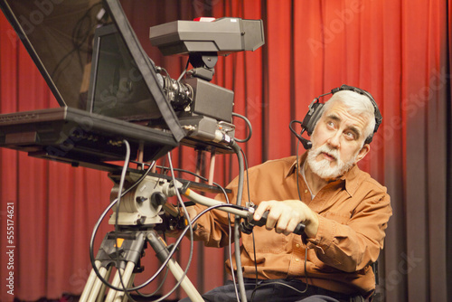 Man in wheelchair with muscular dystrophy using a TV camera and a teleprompter in studio photo