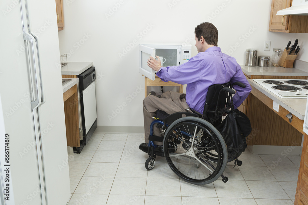 Man in wheelchair with spinal cord injury opening accessible microwave Man in wheelchair with spinal cord injury opening accessible microwave