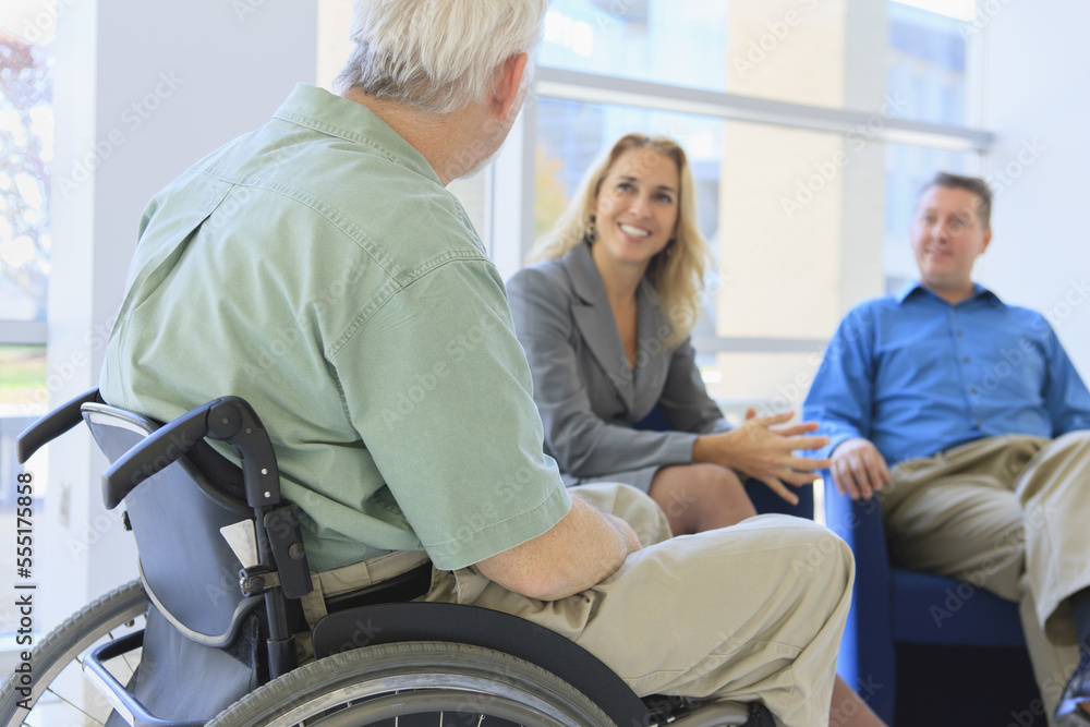 Man with Muscular Dystrophy in a wheelchair talking with friends Man with Muscular Dystrophy in a wheelchair talking with friends