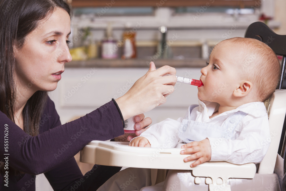 Mother giving medicine to her son