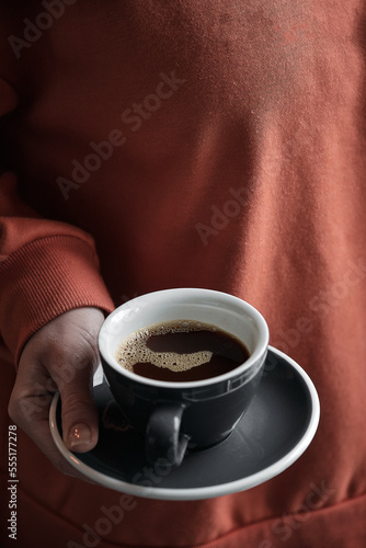 Girl in red sweater holds a cup of coffee
