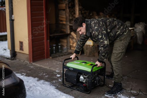 Man wear in military jacket with gasoline portable mobile backup standby generator. photo
