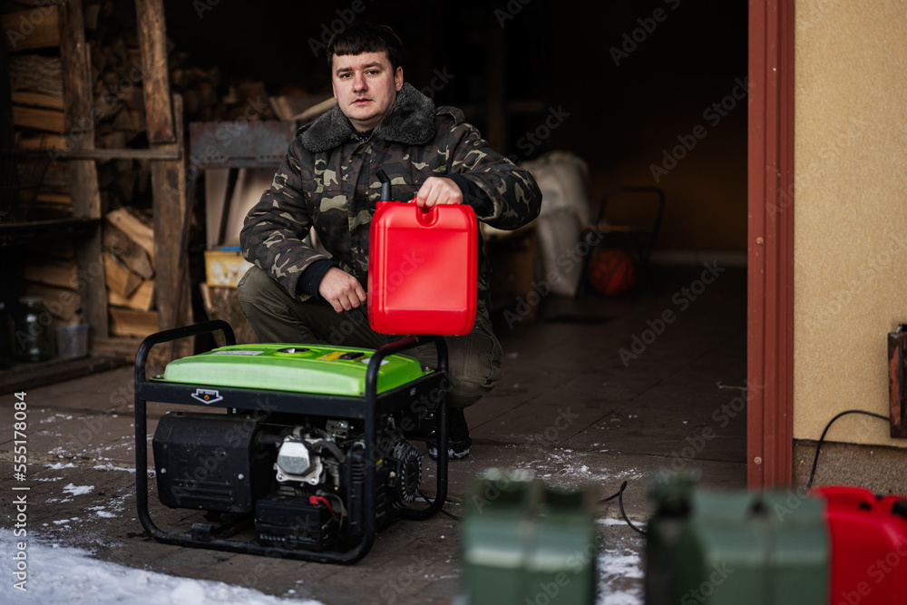 Man wear in military jacket pour gasoline from canister in portable mobile backup standby generator.
