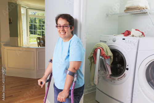 Woman with cerebral palsy washing clothes in the laundry room and smiling photo
