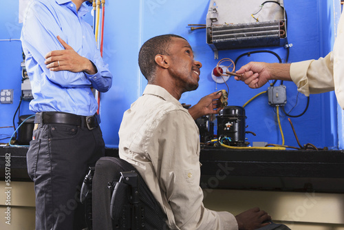 Instructor discussing condenser coil on refrigeration unit with student in wheelchair photo