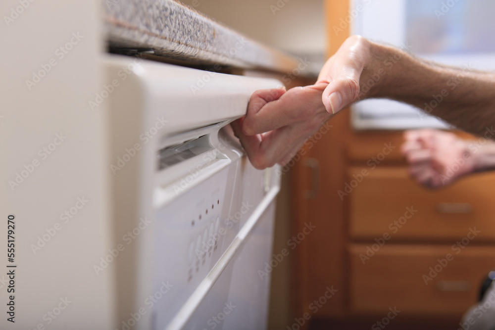 Man with Friedreich's Ataxia and deformed hands using his dishwasher Man with Friedreich's Ataxia and deformed hands using his dishwasher